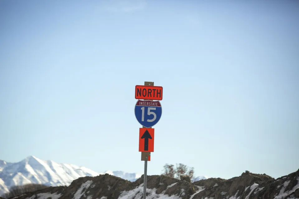 Blue and white Interstate 15 North sign against backdrop of blue sky and snow-capped mountains in Utah
